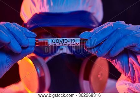 COVID-19 or 2019-nCoV. Close-up portrait of a scientist microbiologist in a protective PPE suit showing the tes with a vaccine against coronavirus. Vaccination.