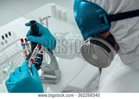 COVID-19. Doctor, microbiologist, scientist in a protective suit, makes a study of coronavirus in the laboratory. Coronavirus test.