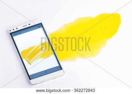 Picture Of Spilled Orange Juice In Your Smartphone. The Juice Flows From The Smartphone To The Table