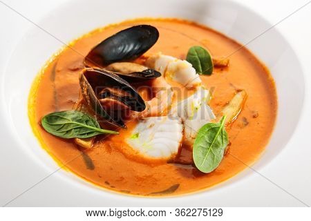 Bouillabaisse in white bowl. Served main course close up. French seafood, soup with fish and mussels. Restaurant food portion, main course. France cuisine. Dinner, gourmet meal in plate