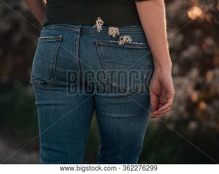 girl in jeans with flower in backpocket
