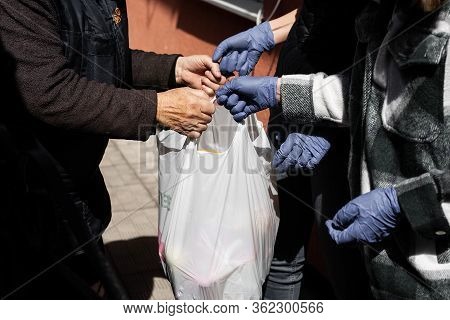 Young People Helping Old Woman With Products. Hands In Gloves, Help During Quarantine 
Through Coron