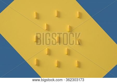 Yellow Capsules Are Laid Out On A Yellow Background With Elements Of A Blue Background. Concept For 