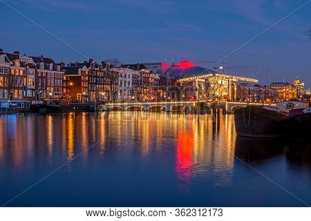 City scenic from Amsterdam at the river Amstel with the Tiny bridge in the Netherlands at night