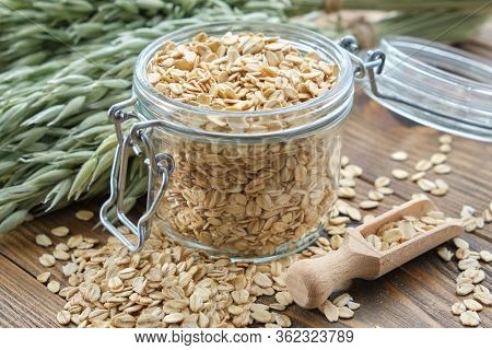 Jar Of Oat Flakes And Green Oat Ears On Wooden Table.