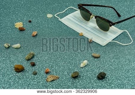 Mask Protection With Man Sunglasses, Stones And Shells On Ground. No Holiday, Stay At Home. Covid-19