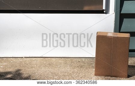 A Small Brown Cardboard Package Is Delivered And Left Exposed To Theft At The Front Door Stoop Of A 