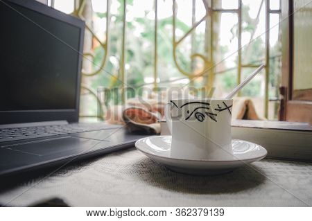 A Cup Of Coffee A Book And Laptop On Window Sunlight In Morning. A Daily Routine During Social Dista
