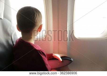 Child Looking Through Porthole In Passenger Plane