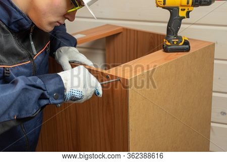 Furniture Maker Assembling Furniture With Screwdriver. Assembly Of Furniture