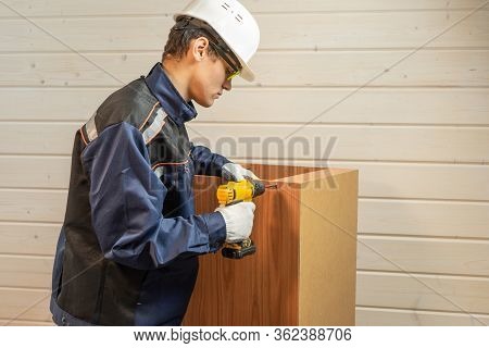 The Repairer In Assembly Of Furniture Collects New Furniture. Young Repairman Assembling New Table A