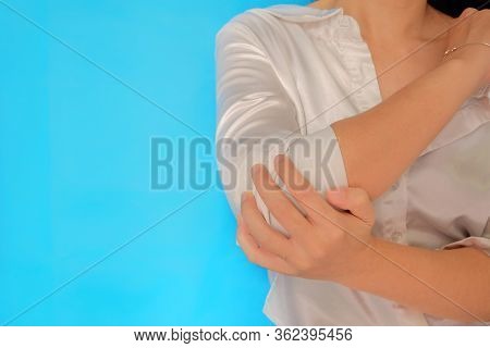 A Front View Of Woman Mid Body Using Her Hand To Rub Her Elbow With Joint Pain. Plain Light Blue Bac