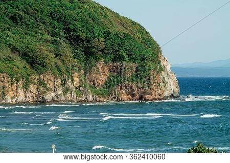 Seascape, Beautiful View Of The Rocky Cliff In The Sea With Mountains On The Horizon