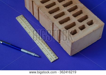 Brick, Pen And Wooden Ruler. Single Brick And Stationery On A Blue Background. Construction Industry