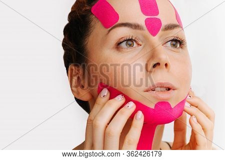 Calm Relaxed Woman Sencing, Touching Kinesio Tape On Her Chin Over White