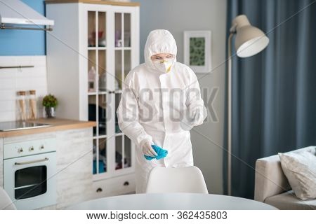 Woman In White Workwear Disinfecting The Apartment