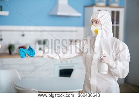 Woman In White Workwear And Protective Gloves Holding A Duster In Her Hand