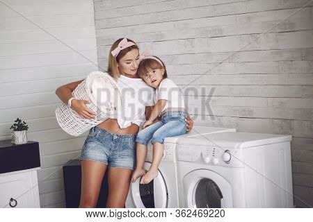Mother And Daughter In A Bathroom Near Wash Mashine