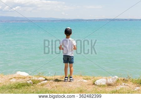 Boy Stands On Coast Of Lake, Sunny Daytime. Healthy Leisure. Summer. Calmness. Nature. Panoramic Vie