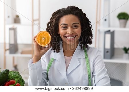 Vitamin C Is Good For Immunity. Portrait Of Smiling Female Doctor Dietologist Holding Orange Half, R