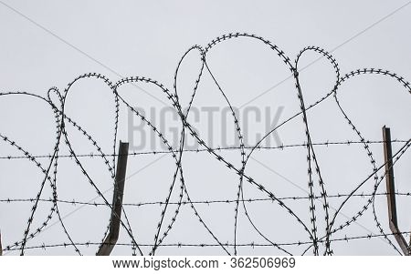 Concertina Wire. Grey Cloudy Sky Over Shot