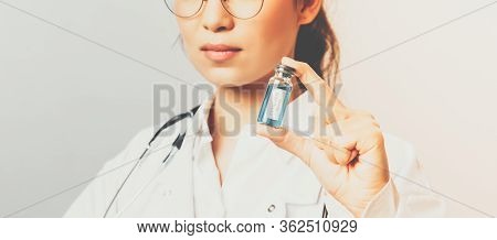 Close-up Portrait Of Serious-looking Young Asian Infectionist, Female Doctor Showing Ampule With Cor