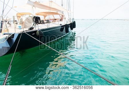 Ship's bow and aquamarine water in the port of Syracuse, Sicily. Boat and sea, detail. Sailing vessel drops anchor in a quiet bay