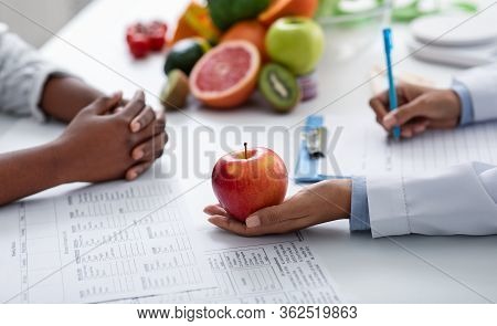 Close Up Of Dietologist And Patient Female Hands Over Doctor Workplace, Nutritionist Holding Apple