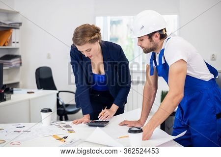 Two Engineers, A Man And A Woman, Working On The Technical Drawi