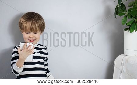 Little European Child Blond Child Plays, Looks At The Smartphone Cell Phone And Rejoices Smiling Lau