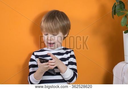Little European Child Blond Child Plays, Looks At The Smartphone Cell Phone And Rejoices Smiling Lau