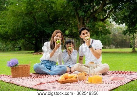 Asian Teen Family Happy Holiday Picnic Moment In The Park With Father, Mother And Daughter Eating Gr