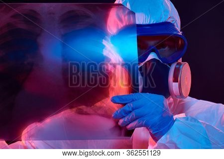 COVID-19 or 2019-nCoV. Portrait of a doctor in a protective PPE suit showing an x-ray picture of the lungs of a patient with coronavirus pneumonia. 