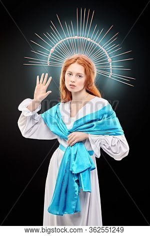 The Virgin Mary portrait on a dark background with rays of light. Modern art in religion. 