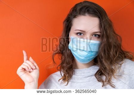 A Young Doctor In A Medical Mask Points To A Poster. Space For Your Text. Medical Design Concept.
