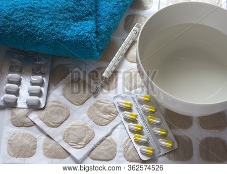 Mustard Sheets With Medicine And A Thermometer For Treating Colds With A Blue Towel And Water Are Re