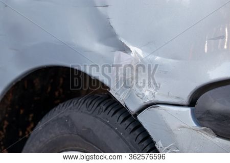 Damaged Bumper On A Grey Car. Paint Scratched. Botched Bad Repair Job With Duct Tape, Body Parts Bar