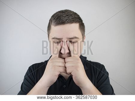 Nasal Bridge Pain, Headache. A Man Holds His Nose With His Hand And Winces In Pain. Signs Of Acute E
