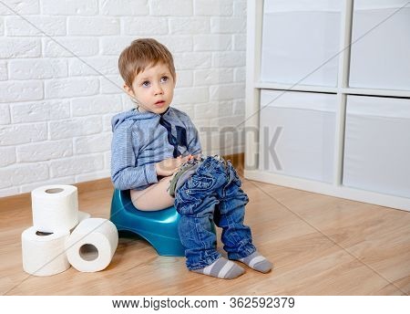 Child Sitting On The Potty With Toilet Paper. Colic, Bloating, Pain