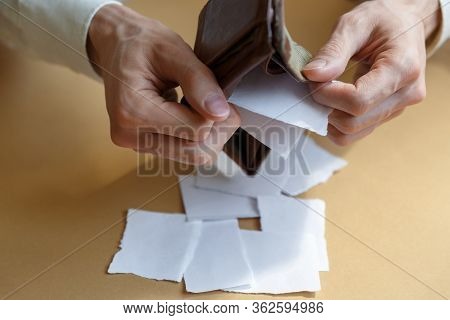 Side View Of A Man Shaking Pieces Of Paper From An Empty Wallet On A Light Monophonic Background. Ba