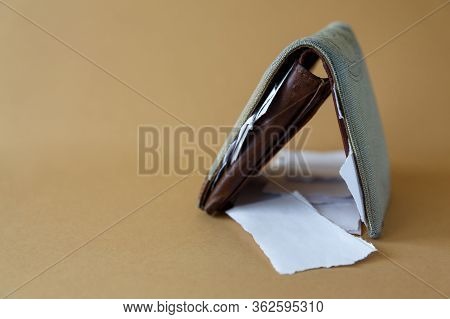 Side View Of An Empty Wallet With Pieces Of Paper Instead Of Money On A Light Monophonic Background.