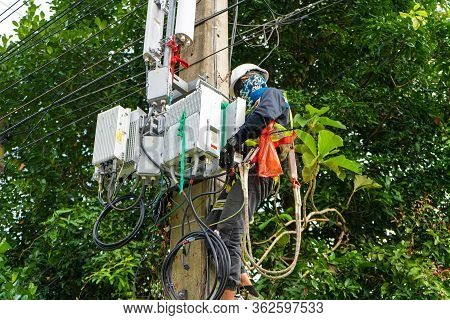 A Professional Electrician Performs Installation Work On A Pole. An Electrician In Professional Equi