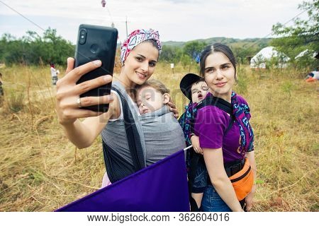 Almaty, Kazakhstan - 15 August 2019. Foure Ethnic Festival, Two Babywearing Mothers Making Selfie Wi