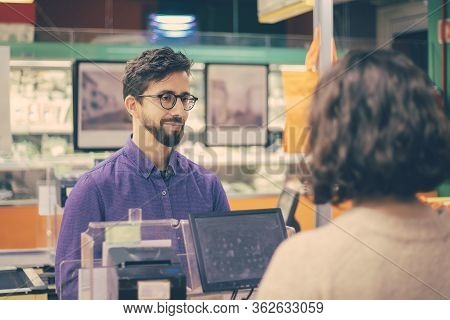 Man And Woman Talking At Pay Desk In Grocery Store. Customer Talking With Cahier While Buying Goods 