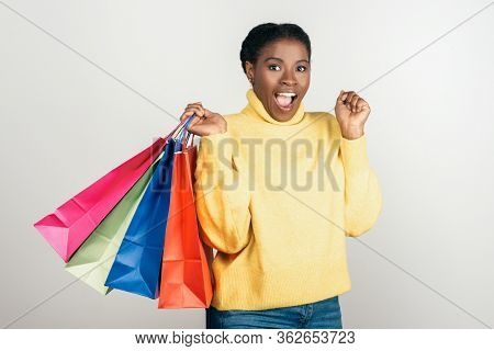 Excited African American Woman With Shopping Bags. Agitated Attractive Young Lady With Raised Hands 
