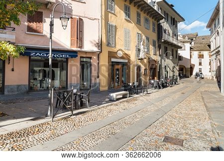 Pedestrian Street With Typical Outdoor Bars And Shops In The Historic Center Of Domodossola, Italy.