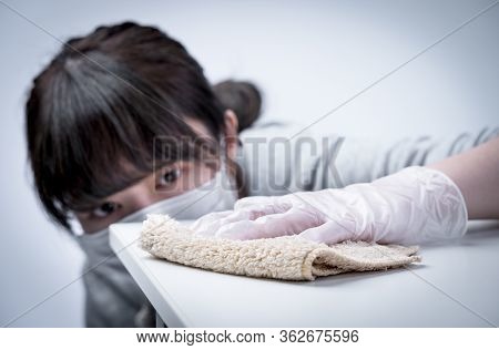 Young Woman Housewife Is Cleaning, Wiping Down Home Table Surface To Stop The Spread Of Infection Wi