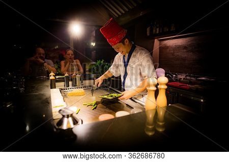 May, 2018 - Ari Atoll, Maldives: Happy Teppanyaki Chef Cooking Vegetables At Teppan In A Japanese St