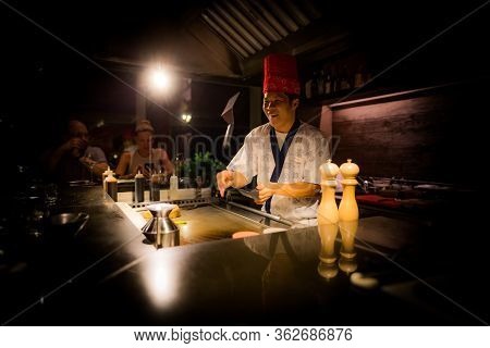 May, 2018 - Ari Atoll, Maldives: Happy Teppanyaki Chef Cooking Vegetables At Teppan In A Japanese St