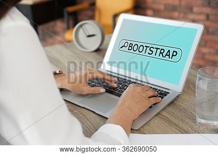Woman Using Modern Laptop At Table In Office, Closeup. Bootstrap Button